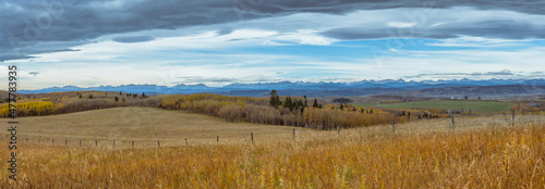 Canadian Rocky Mountain range and prairie fall color landscape panoramic background. Old wooden fence in a grassy field panorama 
