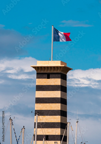 Deauville, France - August 6, 2021: The Marina Port and its tower with french flag in Trouville, Normandy, France.