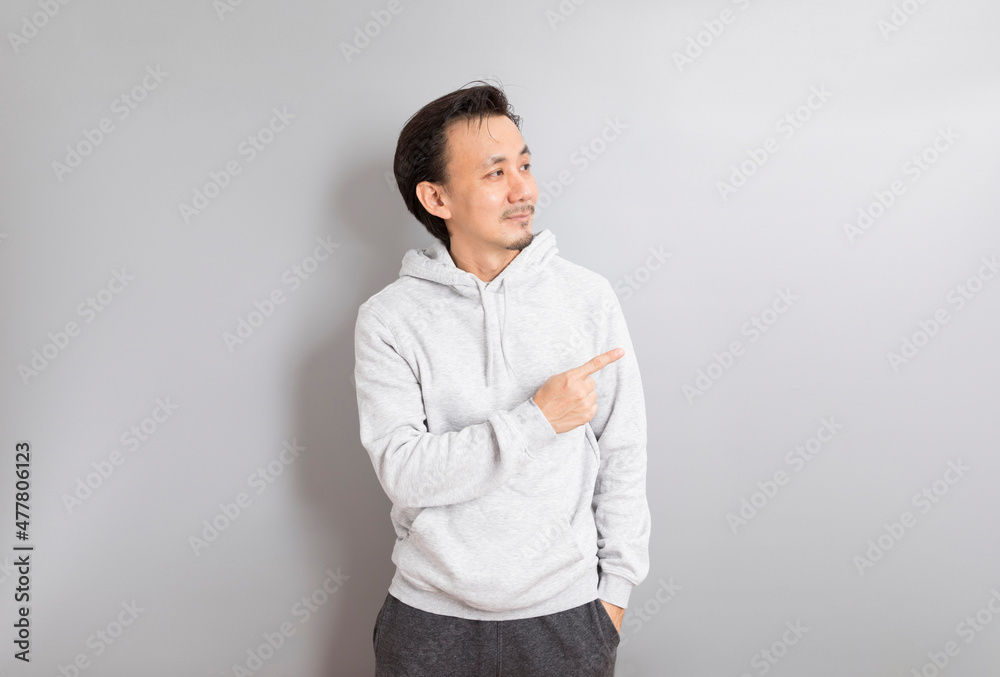 Adult Asian Man in hoodie Wear eyeglasses and Pointing Finger on Gray Background. Adult Asian Man in hoodie Wear eyeglasses and Pointing Finger on Gray Background.