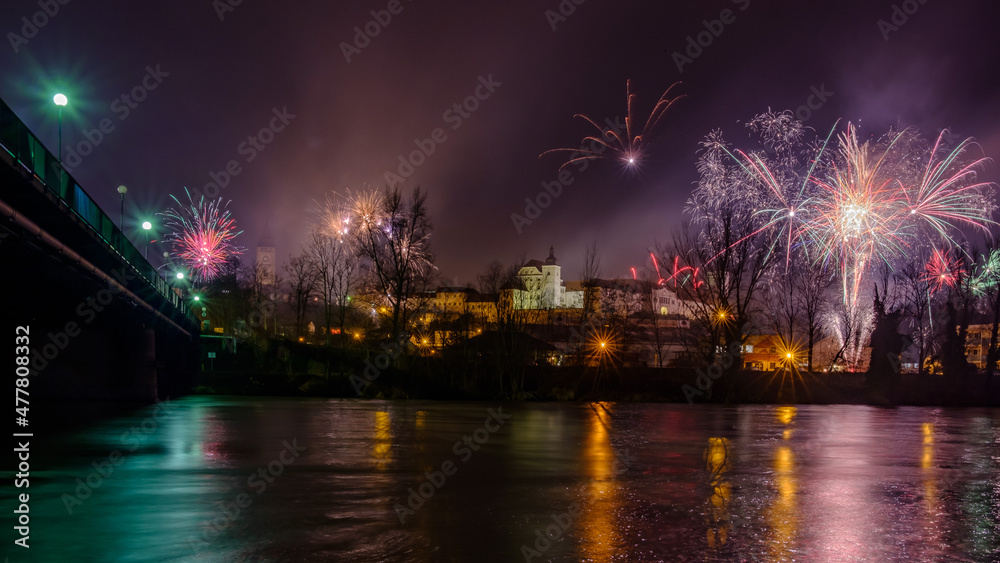 silvester fireworks over enns, upper austria, seen from ennsdorf with the river enns