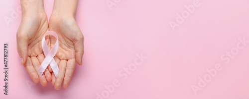 Female hands with pink ribbon on color background with space for text. Breast cancer concept photo