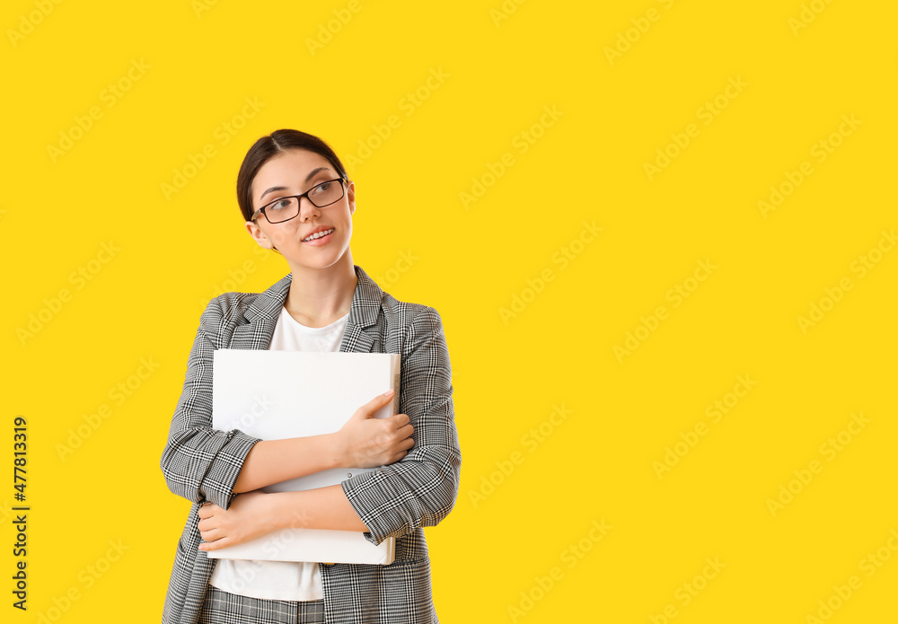 Teenage girl in eyeglasses with white folder on yellow background Teenage girl in eyeglasses with white folder on yellow background