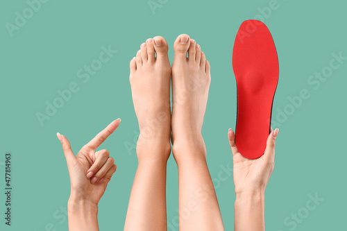 Woman with red orthopedic insole pointing at her feet on green background photo