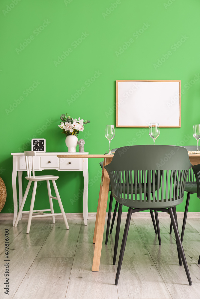 Fototapeta premium Interior of stylish dining room with tables, frame and green wall