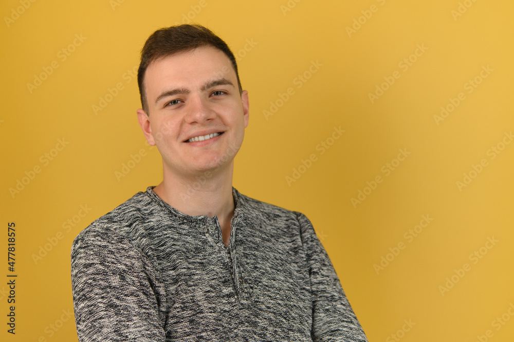 A young attractive man is standing with his arms crossed over his chest and smiling at the camera A young attractive man is standing with his arms crossed over his chest and smiling at the camera