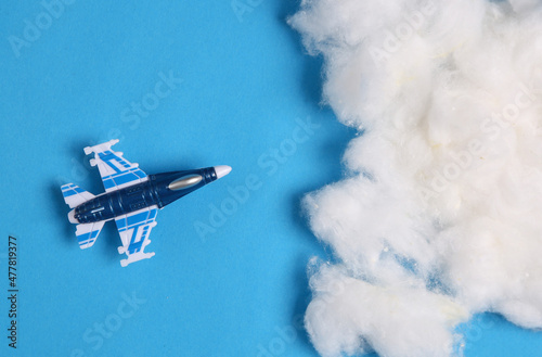 Fototapeta Naklejka Na Ścianę i Meble -  Toy fighter plane on blue background with clouds