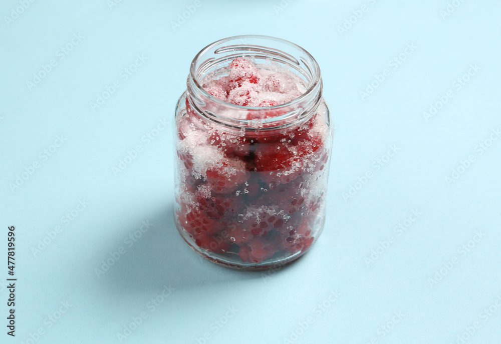 Glass Jar of raspberries with sugar on a blue background Glass Jar of raspberries with sugar on a blue background