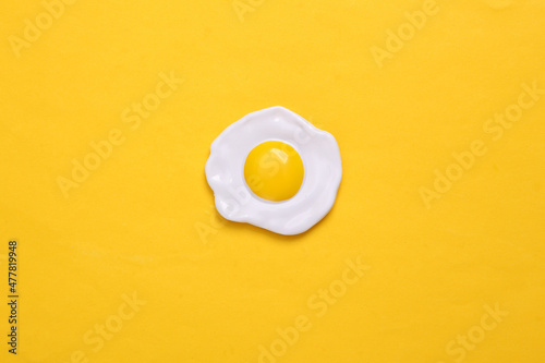 Plastic scrambled eggs on yellow background. Top view. Minimal food concept photo