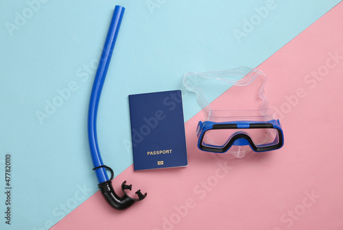 Diving goggles, snorkel and passport on pink blue background. Travel concept. Flat lay