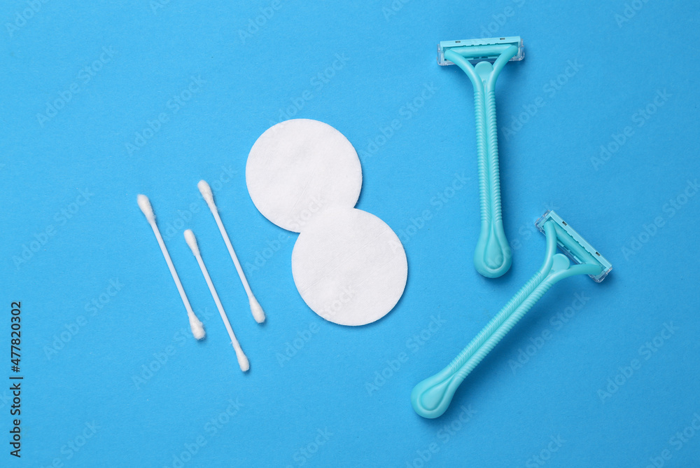 Hygiene, body care concept. Shaver depilator, cotton pad and sticks on a blue background. Top view Hygiene, body care concept. Shaver depilator, cotton pad and sticks on a blue background. Top view