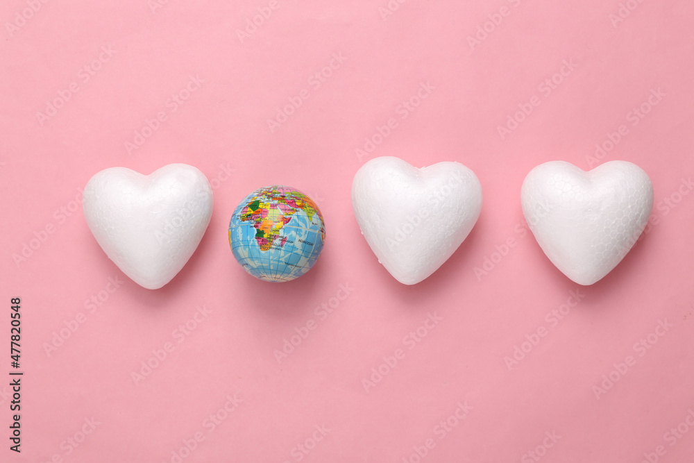 Globe with hearts on pink pastel background. World love day