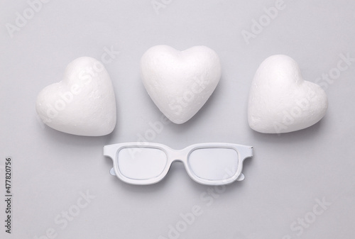 Love layout. White painted glasses and hearts on a gray background