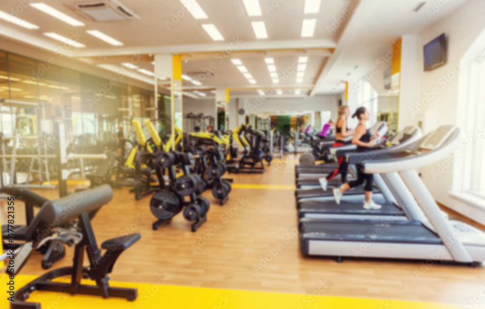 Fototapeta premium Blurred image of a modern gym with people exercising. Sports background. Gym interior