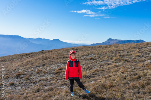 Boy 8 years old in a red jacket on the top of a mountain after a long climb during a hike