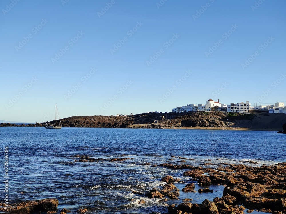 Paisaje costero con pequeño pueblo y barco velero