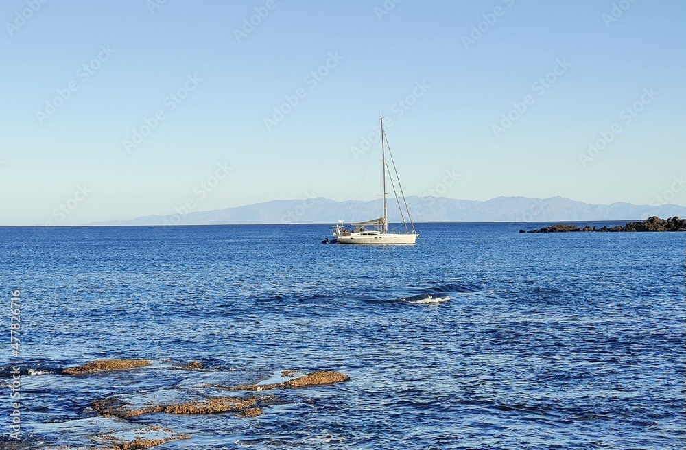 Barco velero e isla en el horizonte