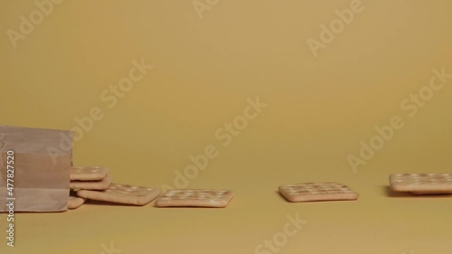 cookies fall out of the craft package on a yellow background. take cookies with your hand.