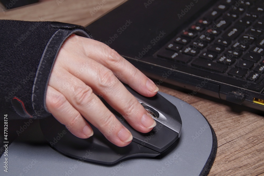 hand in orthosis holding a computer mouse on the computer background