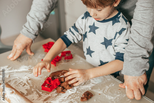 Photo of hands of father mother and son baking cookies. Lay out on baking sheet, cut out with cookie cutters. Happy time with family. Christmas moments. Family have fun