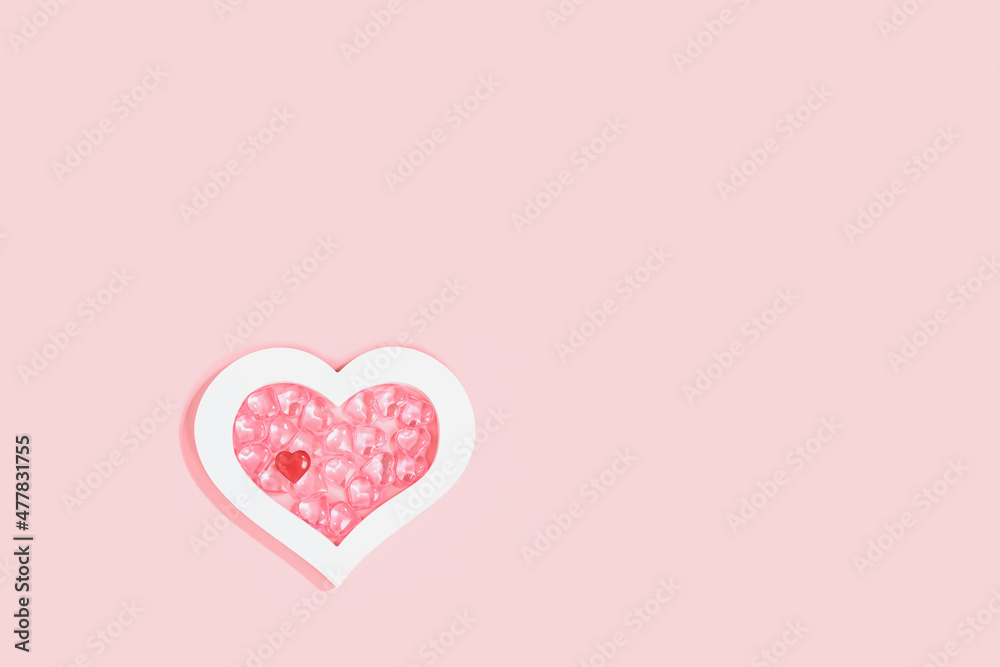 St Valentines day pink background. Many glass hearts within white heart frame flat lay. Love or wedding concept minimal.