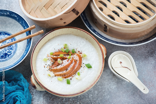 Bowl of asian congee with chicken meat on a roseate metal background, horizontal shot, elevated view photo