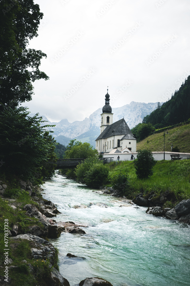 Kirche Sankt Sebastian in Berchtesgaden Bayern Deutschland mit Bergen Wolken Fluss