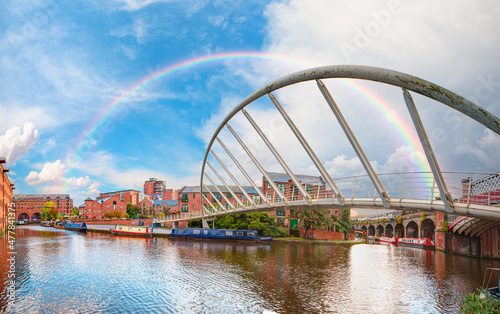 Amazing rainbow over the waterway canal area with a narrowboat on the foreground modern bridge, Castlefield district - Manchester, UK