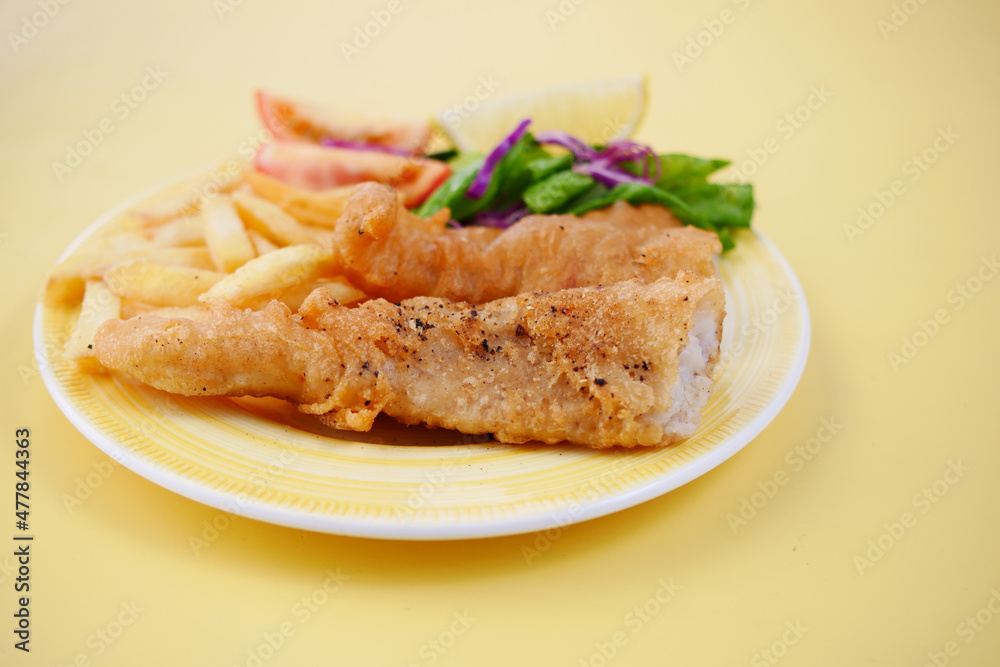 Fish fillet, lemon , chips and potato mash on yellow background 