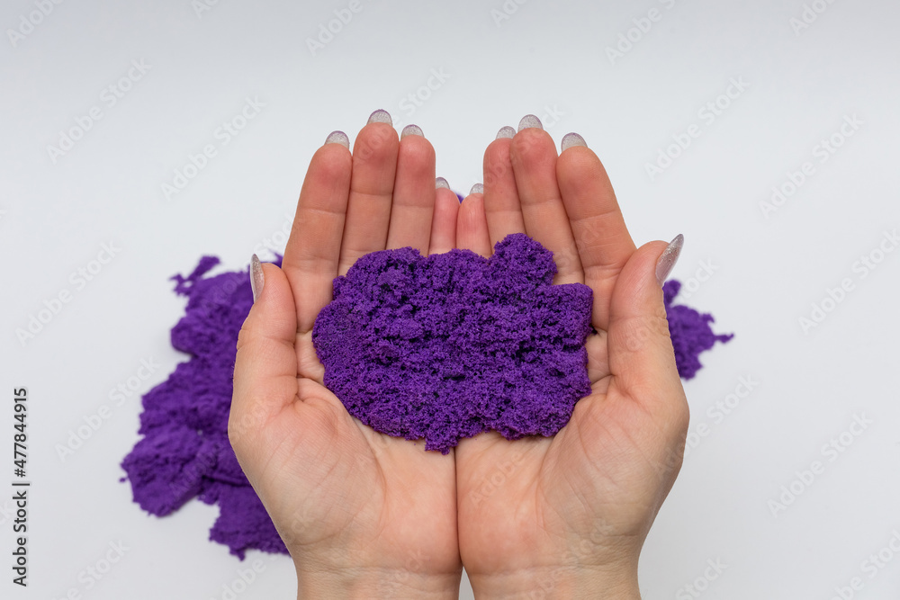 Purple kinetic sand on women's palms. Purple kinetic sand on women's palms.