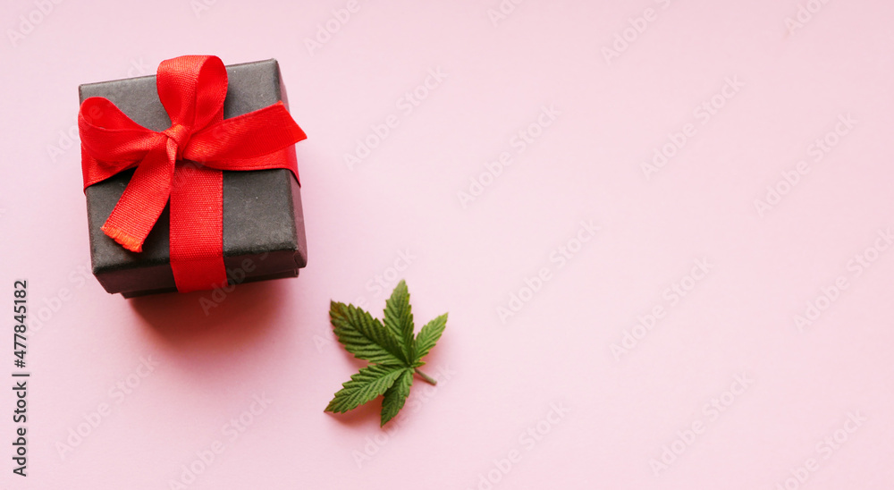Valentine's day greeting. Cannabis leaf with gift box. Pink background. Valentine's day greeting. Cannabis leaf with gift box. Pink background.