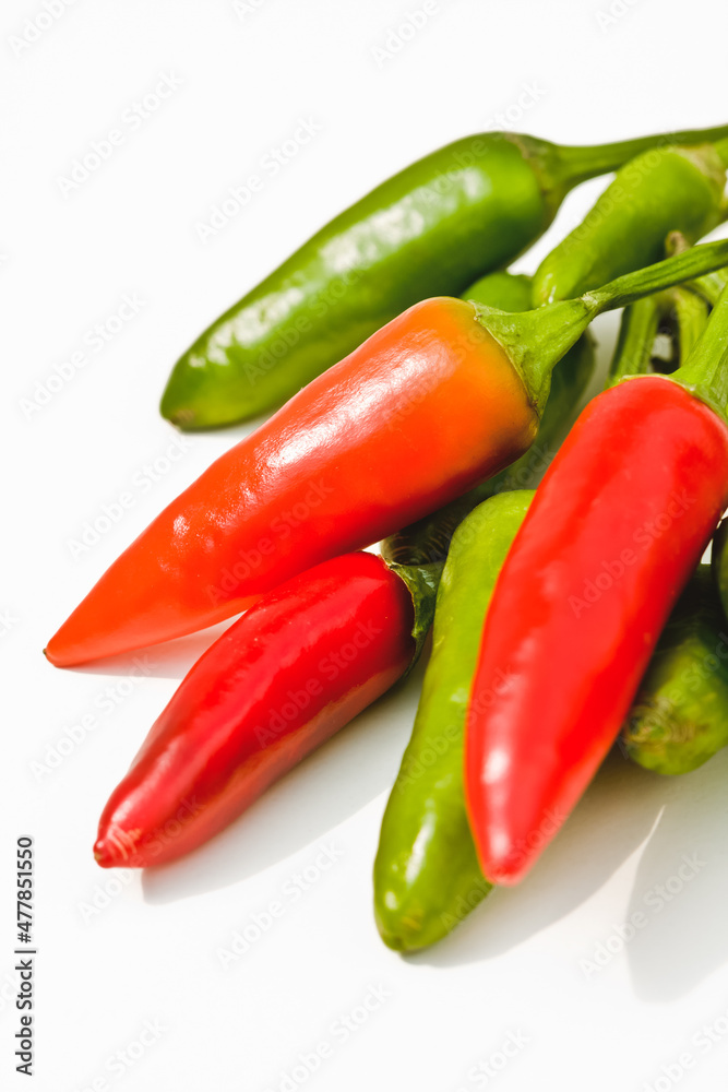 Red and green chilies, against white background, close-up Red and green chilies, against white background, close-up