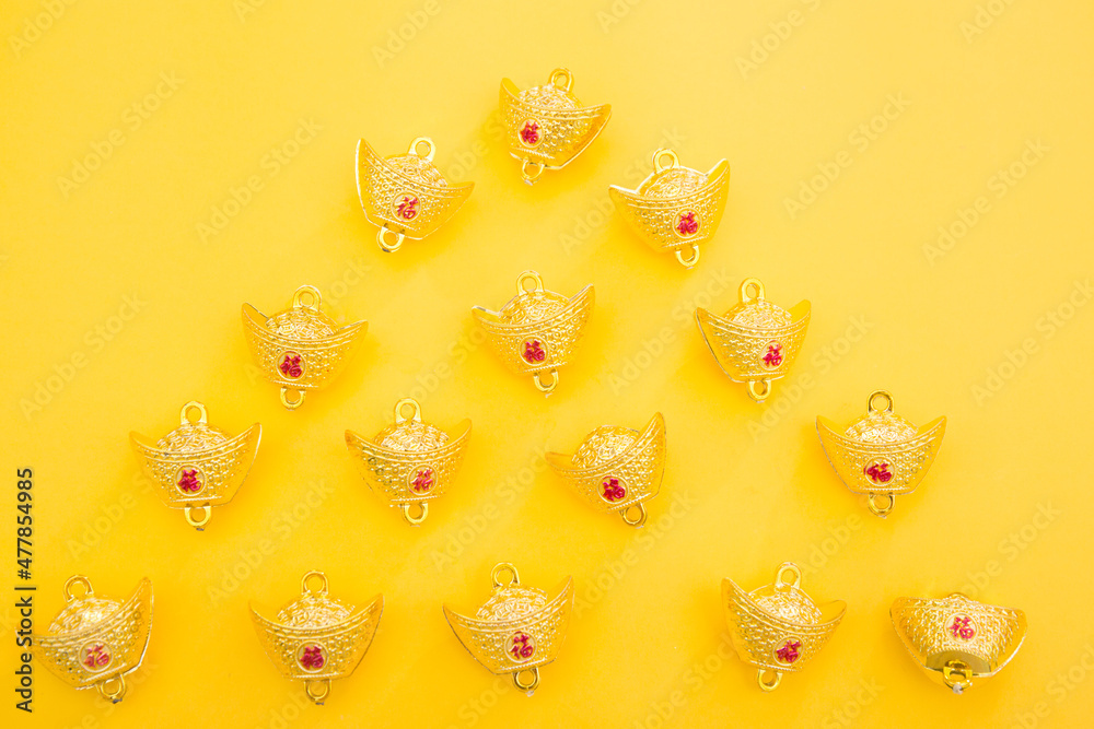 Lunar New Year decoration with lucky gold bar isolated on yellow . Tet Holiday.Translation of text appear in image: fortune good luck	
