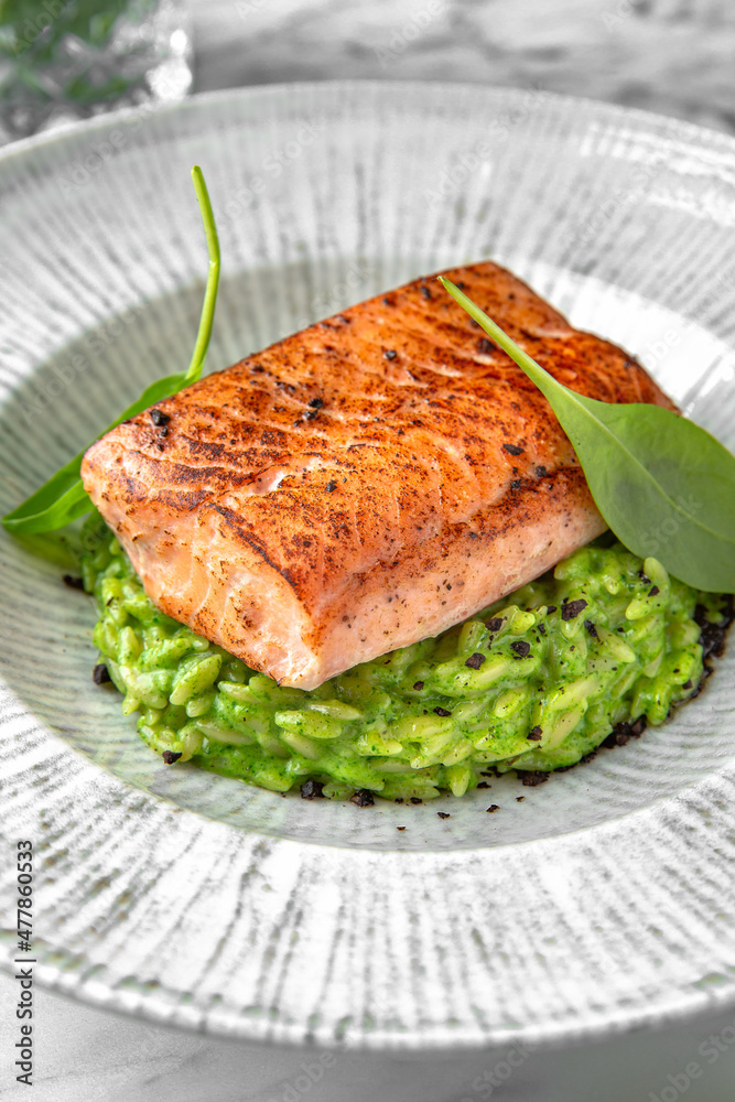 Grilled salmon fillet in avocado sauce in a festive plate on a marble background. Restaurant banquet menu. Grilled salmon fillet in avocado sauce in a festive plate on a marble background. Restaurant banquet menu.