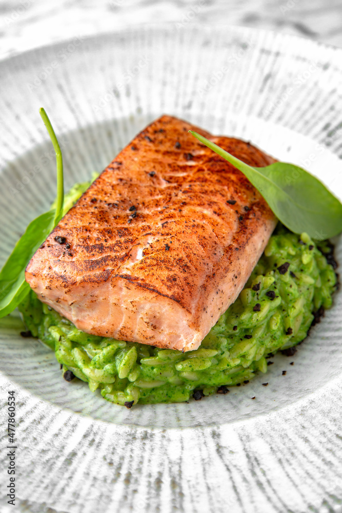 Grilled salmon fillet in avocado sauce in a festive plate on a marble background. Restaurant banquet menu. Grilled salmon fillet in avocado sauce in a festive plate on a marble background. Restaurant banquet menu.