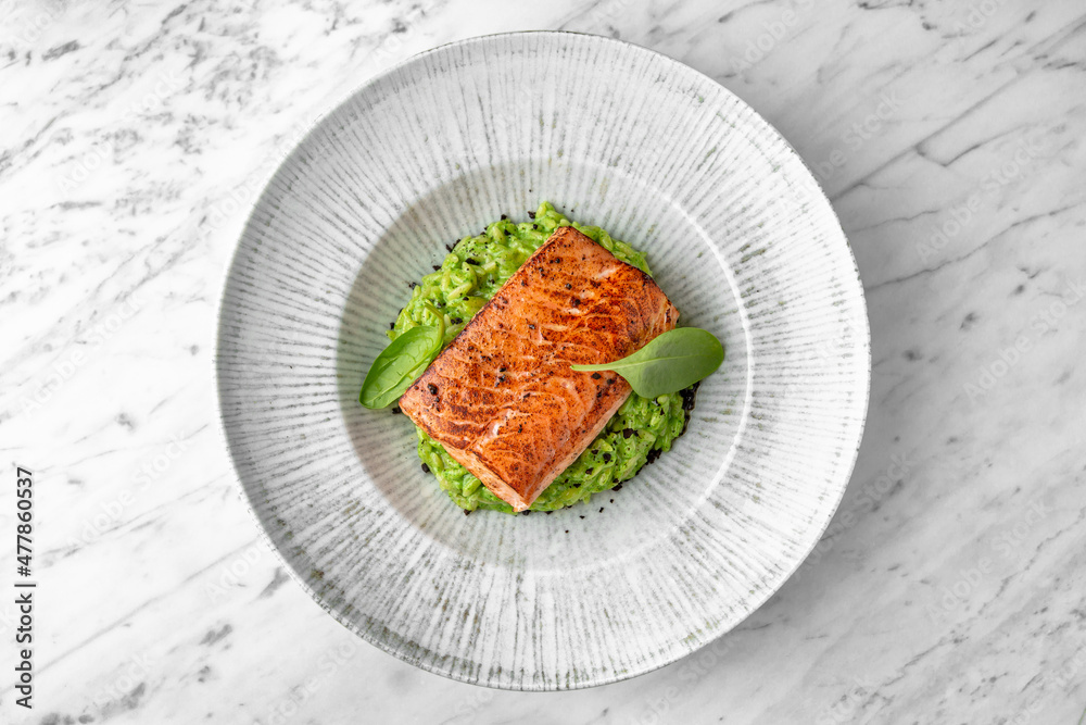 Grilled salmon fillet in avocado sauce in a festive plate on a marble background. Restaurant banquet menu. Grilled salmon fillet in avocado sauce in a festive plate on a marble background. Restaurant banquet menu.