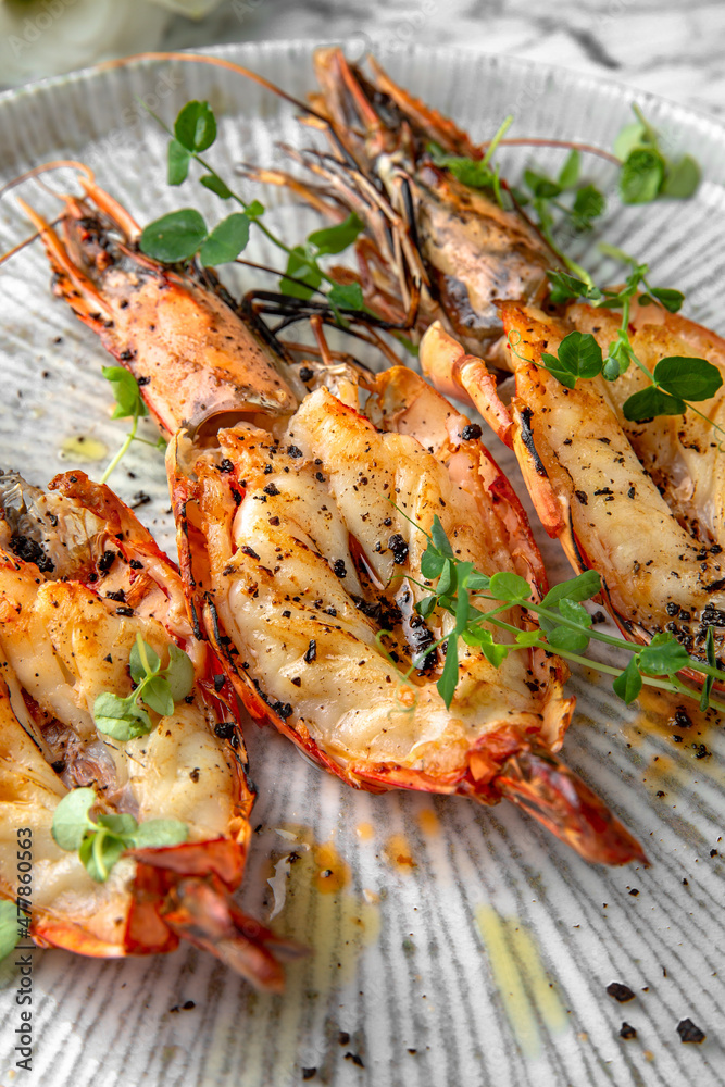 Grilled king prawns in a festive plate on a marble background. Restaurant banquet menu. Grilled king prawns in a festive plate on a marble background. Restaurant banquet menu.