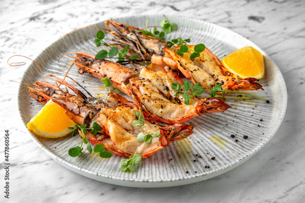 Grilled king prawns in a festive plate on a marble background. Restaurant banquet menu.