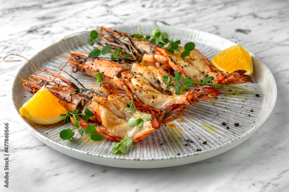 Grilled king prawns in a festive plate on a marble background. Restaurant banquet menu.