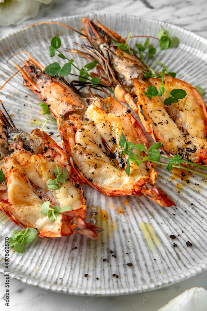 Grilled king prawns in a festive plate on a marble background. Restaurant banquet menu. Grilled king prawns in a festive plate on a marble background. Restaurant banquet menu.