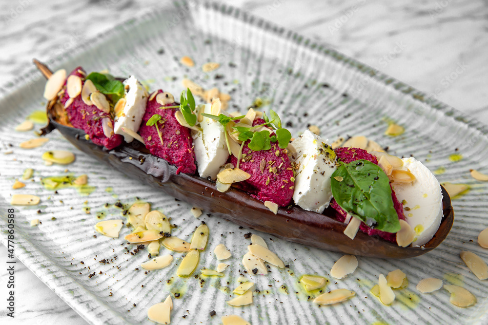 Baked eggplant with beetroot souffle with nuts and mozzarella in a festive plate on a marble background. Restaurant banquet menu. Baked eggplant with beetroot souffle with nuts and mozzarella in a festive plate on a marble background. Restaurant banquet menu.