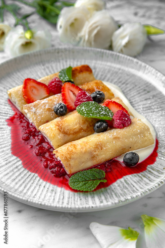 Pancakes or cheese cakes with condensed milk and berries in a festive plate on a marble background. Restaurant banquet menu.