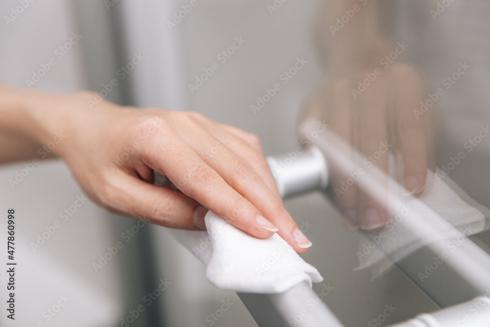 Cleaning glass door handles with an antiseptic wet wipe. Woman hand using towel for cleaning home room door link. Sanitize surfaces prevention in hospital and public spaces against corona virus