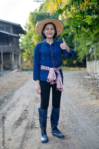 Asian farmer woman wear traditional costume thumb up at farm. Full body portrait.