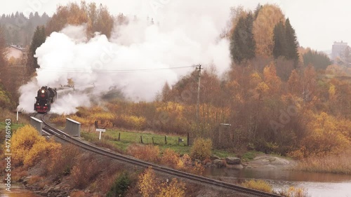 Steam locomotive driving through the embankment across the river