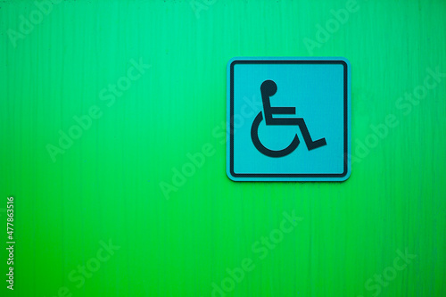 Disabled person sign on the green wall. Copy space