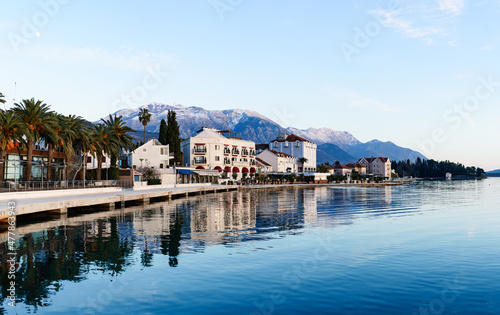Embankment of the town of Tivat surrounded by green palm trees against the backdrop of mountains