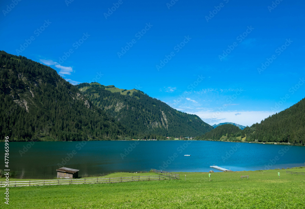 Panorama view of a idyllic summer landscape with clear mountain lake in the bavarian alps against blue sky.