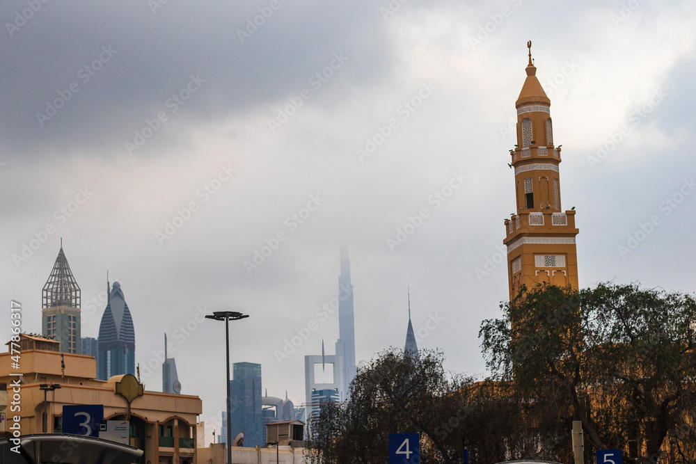 Fototapeta premium Dubai, UAE - 12.22.2021 - Shot of a minaret with cloudy sky on background in Satwa neighborhood. Streets