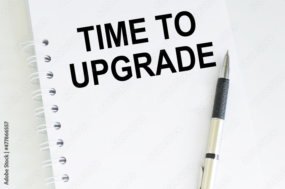 TIME TO UPGRADE text on notepad on a stand next to the pen TIME TO UPGRADE text on notepad on a stand next to the pen
