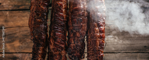 Traditional method of smoking meat in smoke. Smoked ham, bacon, pork neck and sausages in a smokehouse photo
